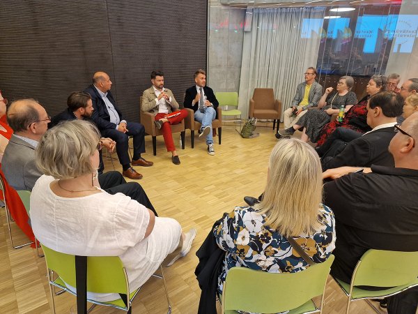 Joukko ihmisiä istuu tuoleilla piirissä keskustelemassa.