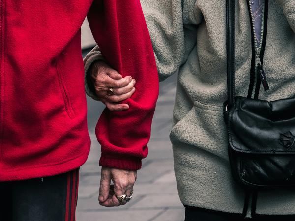 Kaksi ikäihmistä kävelee käsikynkkää.